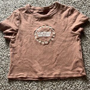 Brown “Nurture Nature” cropped tee for teens.
